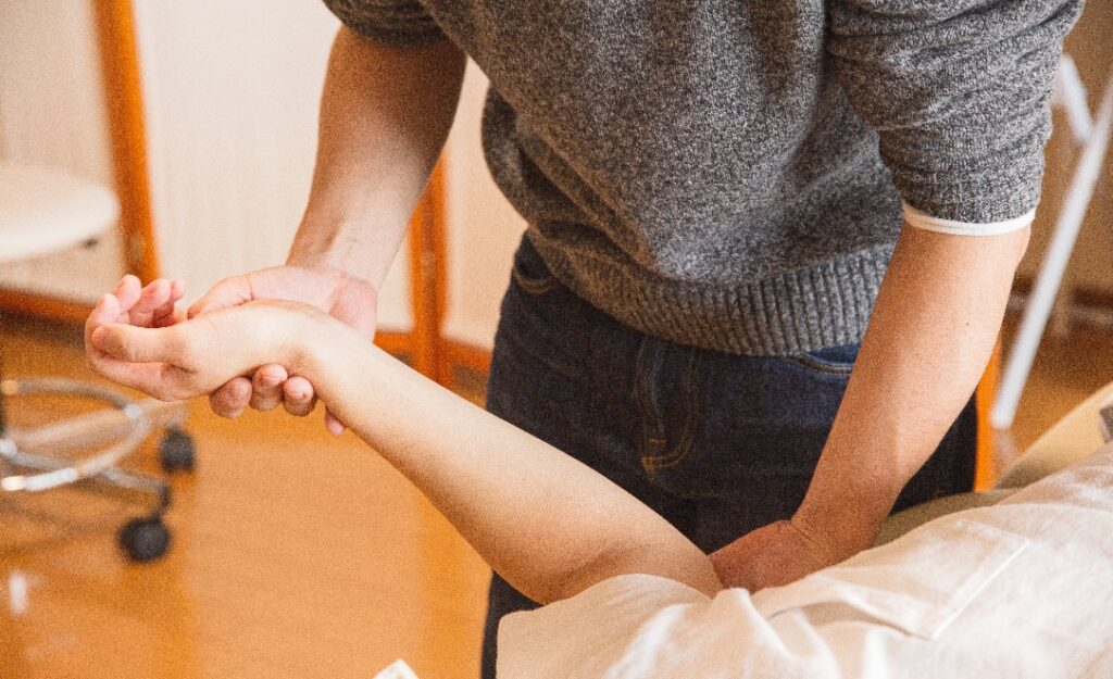 A chiropractor massaging a patient’s hand in a hospital